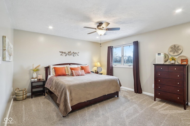 bedroom featuring ceiling fan, light colored carpet, and a textured ceiling