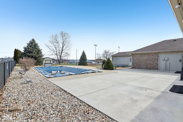 view of pool with a shed and a patio