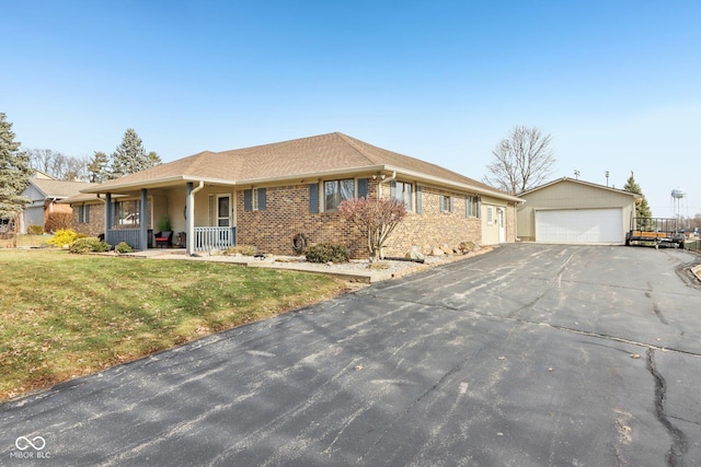 single story home with a garage, an outbuilding, covered porch, and a front lawn