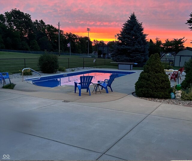 pool at dusk with a yard and a patio area