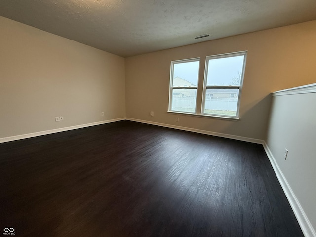 unfurnished room featuring dark wood-type flooring and a textured ceiling