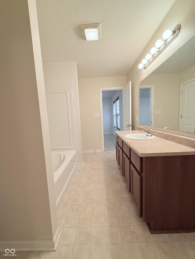 bathroom with tile patterned floors, vanity, a textured ceiling, and a washtub