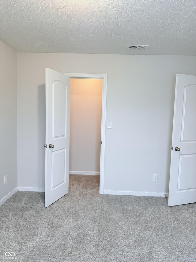 spare room featuring light carpet and a textured ceiling