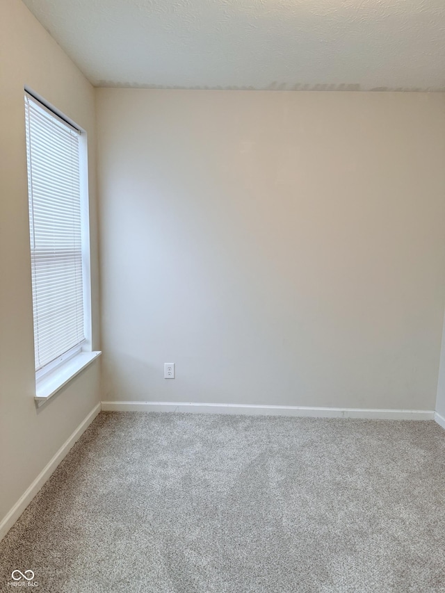 carpeted empty room with a textured ceiling