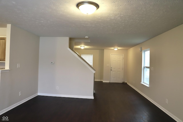 unfurnished room with dark wood-type flooring and a textured ceiling