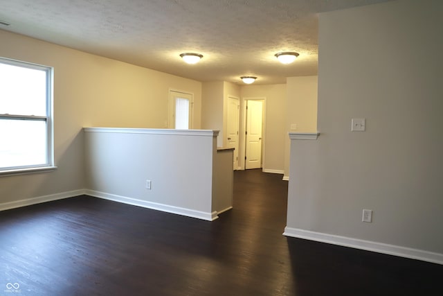 unfurnished room with dark wood-type flooring and a textured ceiling