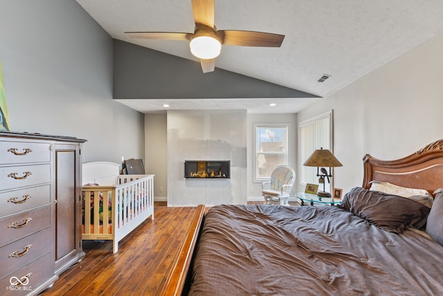 bedroom featuring dark wood-type flooring, lofted ceiling, and a textured ceiling