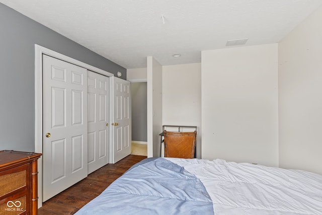 bedroom with a closet, dark hardwood / wood-style floors, and a textured ceiling