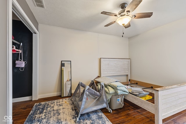 bedroom with ceiling fan, dark hardwood / wood-style flooring, and a textured ceiling