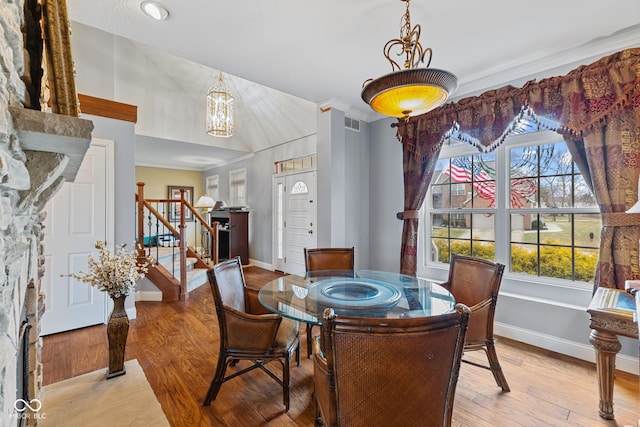 dining area featuring lofted ceiling, a chandelier, and light hardwood / wood-style floors