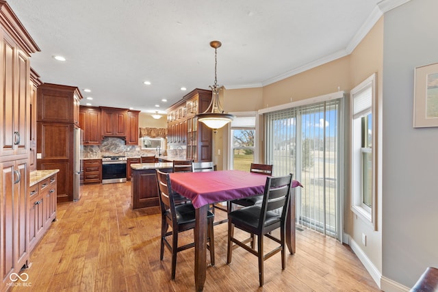 dining area with crown molding and light hardwood / wood-style floors