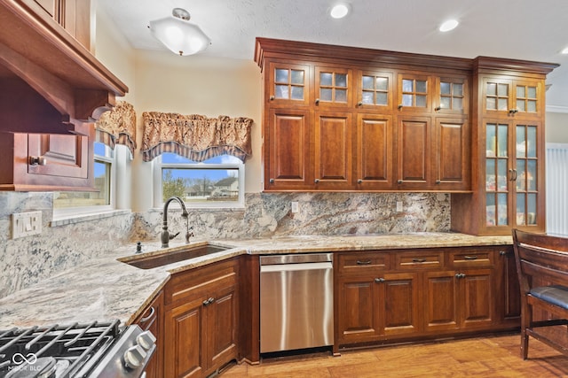 kitchen with dishwasher, light stone countertops, sink, and stove