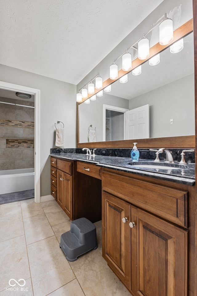 bathroom with tile patterned flooring, vanity, tiled shower / bath combo, and a textured ceiling