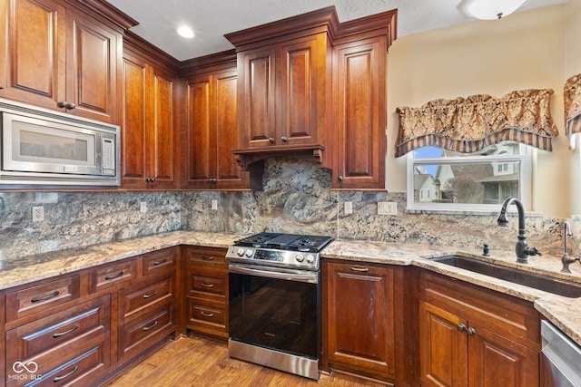 kitchen featuring light stone counters, sink, backsplash, and appliances with stainless steel finishes