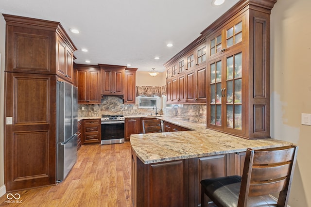 kitchen with sink, appliances with stainless steel finishes, tasteful backsplash, a kitchen bar, and kitchen peninsula