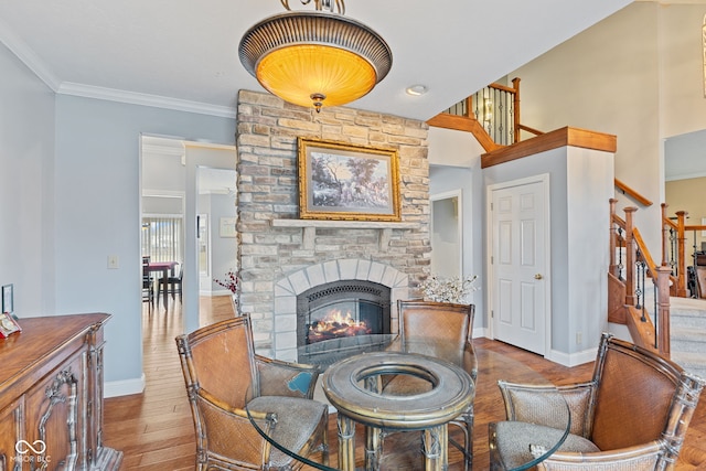 living area featuring ornamental molding, a stone fireplace, and light hardwood / wood-style floors