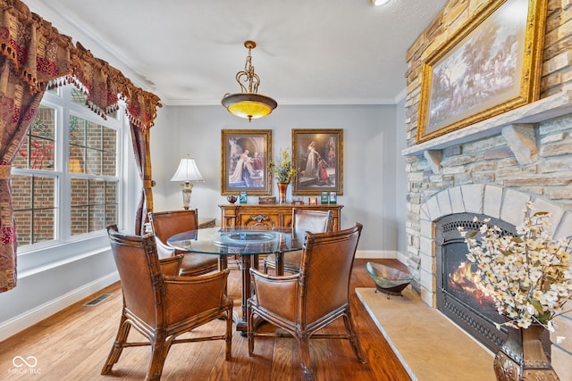 dining room featuring crown molding, wood-type flooring, and a fireplace