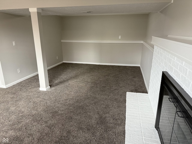 interior space with dark colored carpet, a brick fireplace, and a textured ceiling