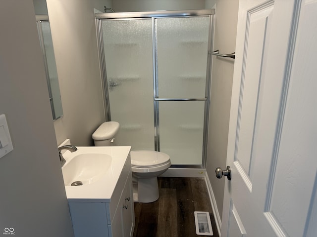 bathroom featuring wood-type flooring, toilet, a shower with door, and vanity