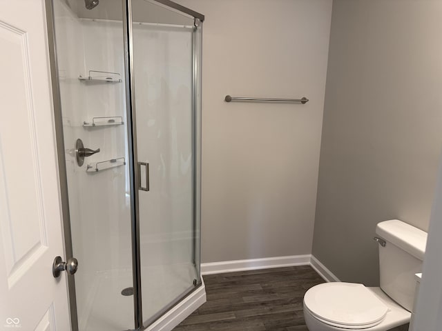 bathroom with hardwood / wood-style flooring, a shower with door, and toilet