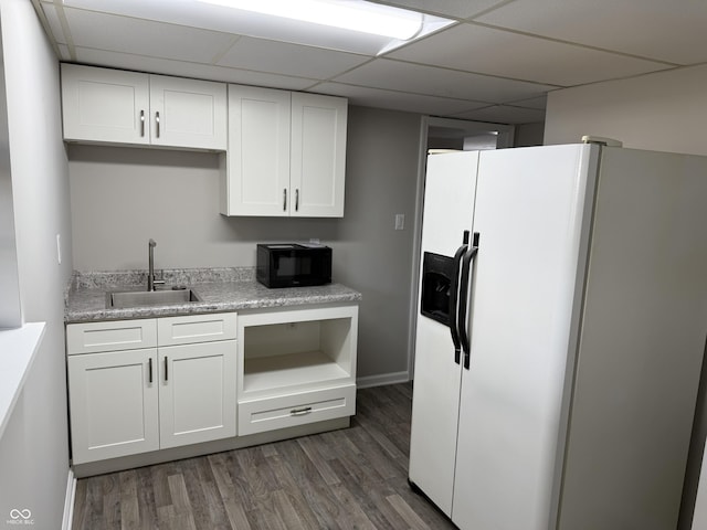 kitchen featuring dark wood-type flooring, sink, white cabinets, white refrigerator with ice dispenser, and a drop ceiling