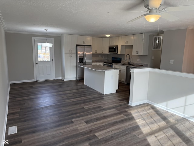 kitchen with sink, ornamental molding, appliances with stainless steel finishes, pendant lighting, and white cabinets