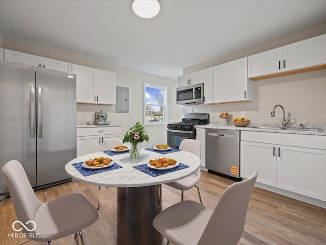 kitchen featuring stainless steel appliances, sink, light hardwood / wood-style flooring, and white cabinets