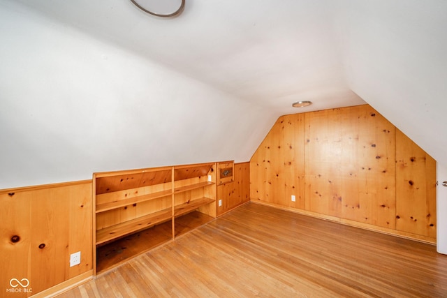 additional living space featuring lofted ceiling, wood-type flooring, and wood walls