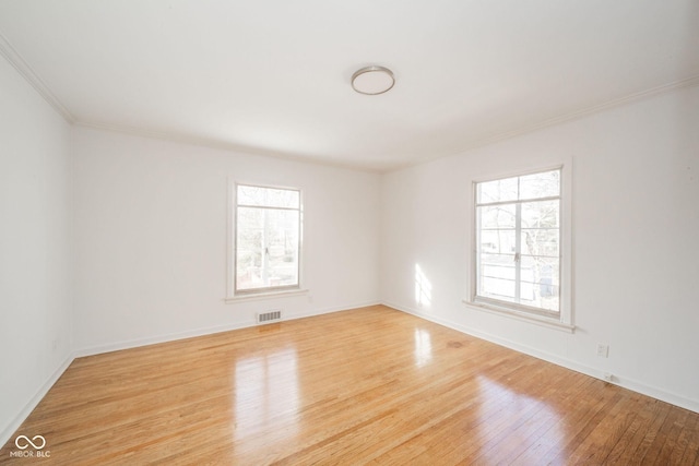 spare room featuring a wealth of natural light, ornamental molding, and light wood-type flooring