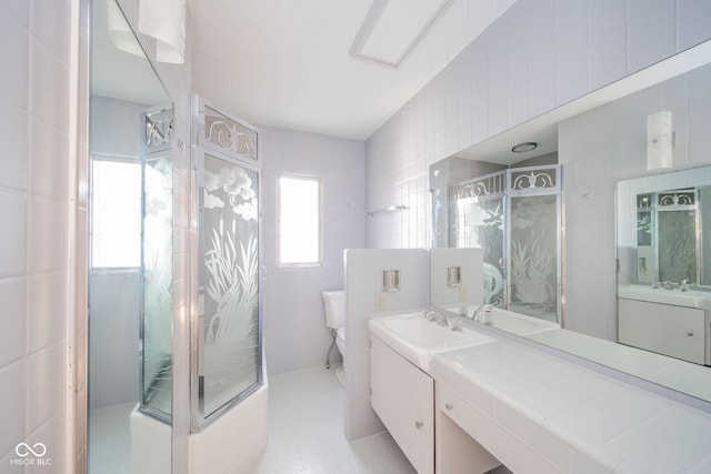 bathroom with vanity, tile walls, toilet, and tiled shower