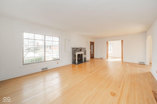 unfurnished living room with crown molding, a premium fireplace, and light wood-type flooring