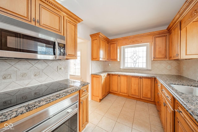 kitchen featuring backsplash, wall oven, sink, and a wealth of natural light