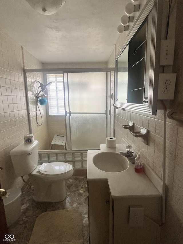 bathroom with tile walls, backsplash, vanity, toilet, and a shower with door