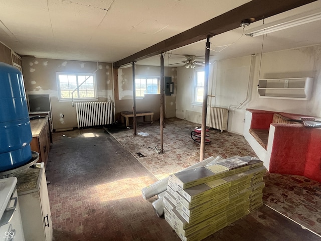 basement featuring radiator, electric panel, and ceiling fan