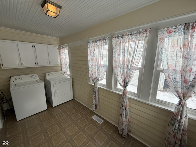 laundry room with cabinets, washer and clothes dryer, and wood walls