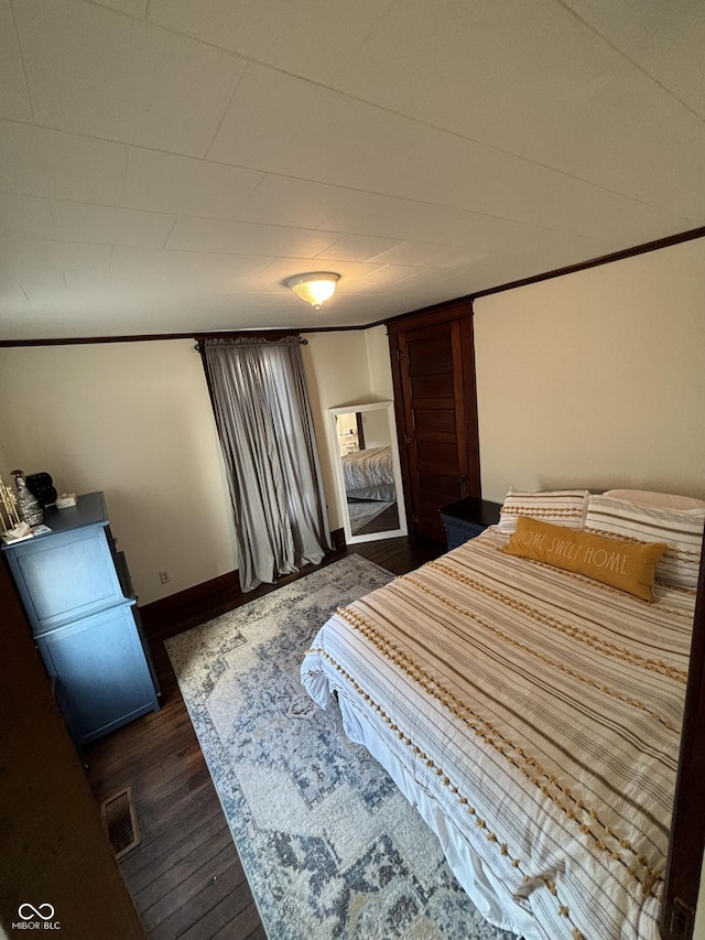 bedroom featuring dark wood-type flooring and crown molding