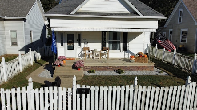 view of front of property with roof with shingles, a porch, and a fenced front yard