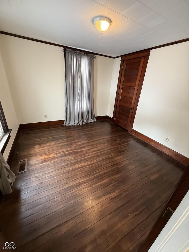 spare room with dark wood-type flooring and crown molding