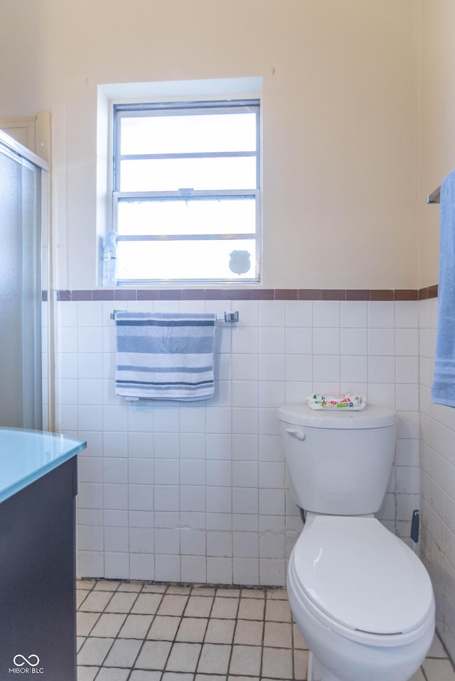 bathroom with tile patterned flooring, vanity, tile walls, and toilet