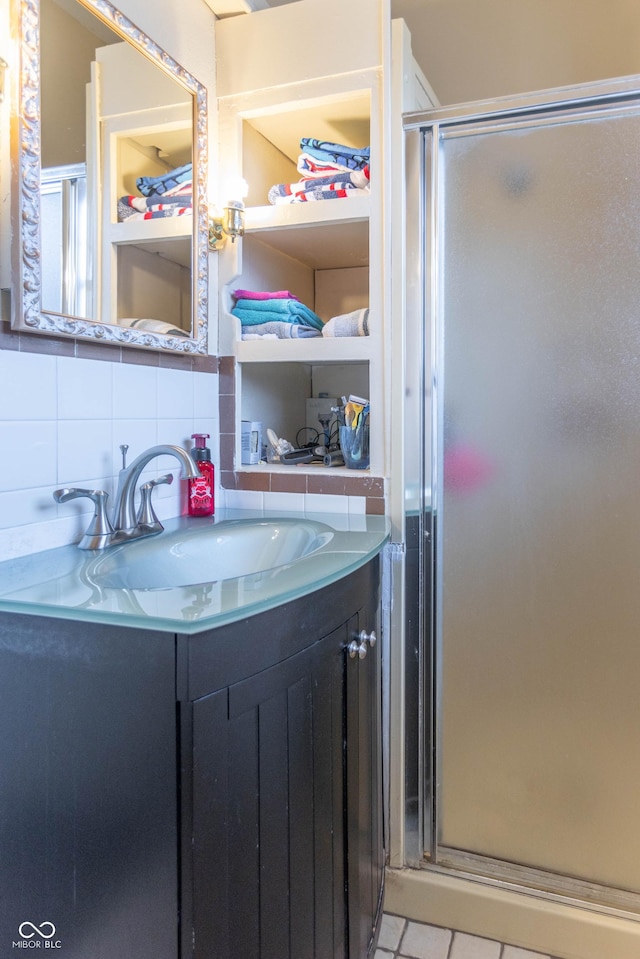 bathroom with vanity, a shower with shower door, and decorative backsplash