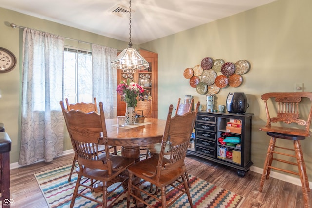 dining room with dark wood-type flooring and a chandelier