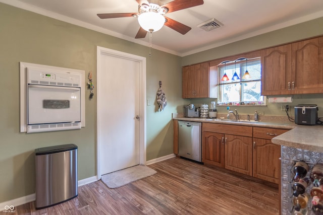 kitchen featuring sink, ornamental molding, stainless steel dishwasher, ceiling fan, and light wood-type flooring