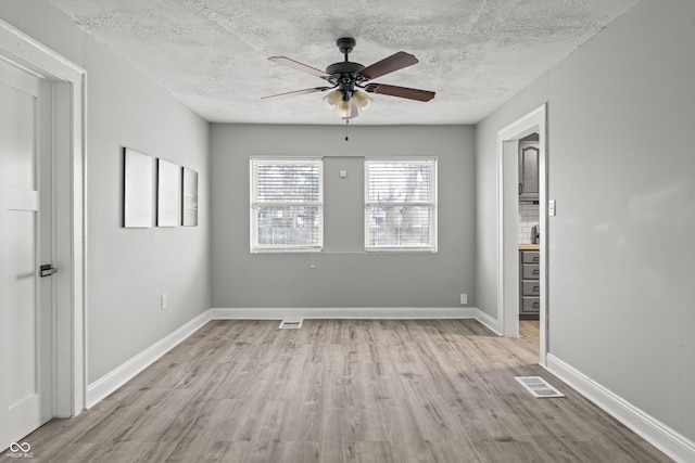 spare room with ceiling fan, a textured ceiling, and light wood-type flooring