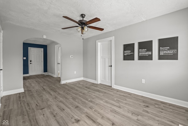 unfurnished room with a textured ceiling, ceiling fan, and light hardwood / wood-style flooring