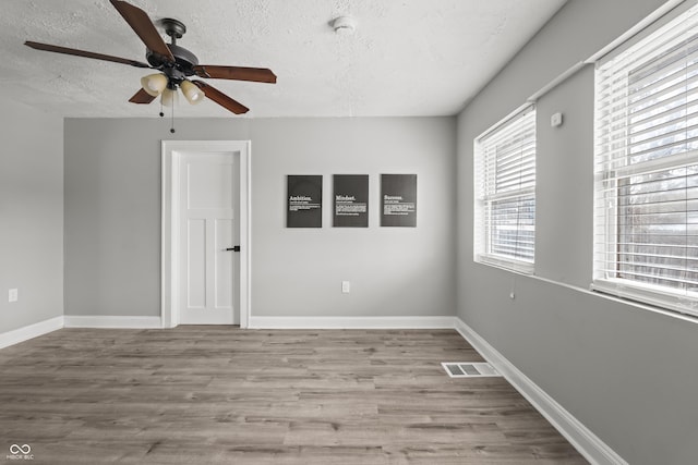 spare room with ceiling fan, a textured ceiling, and light hardwood / wood-style floors