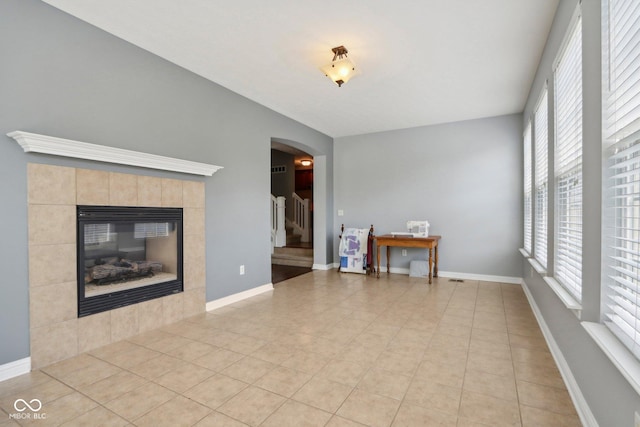 unfurnished living room with a tiled fireplace and light tile patterned floors