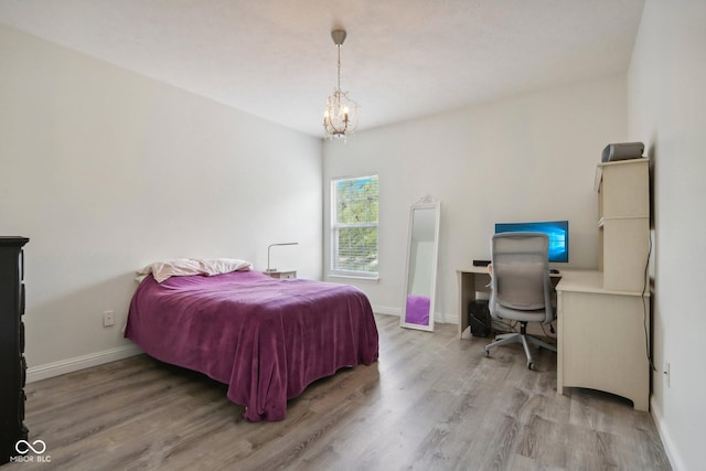 bedroom with hardwood / wood-style flooring and an inviting chandelier