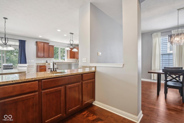 kitchen with sink, pendant lighting, an inviting chandelier, and dark wood-type flooring