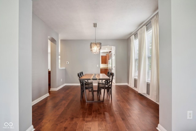 dining space featuring dark wood-type flooring and a notable chandelier