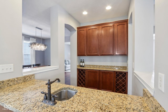 kitchen featuring light stone counters, kitchen peninsula, sink, and pendant lighting